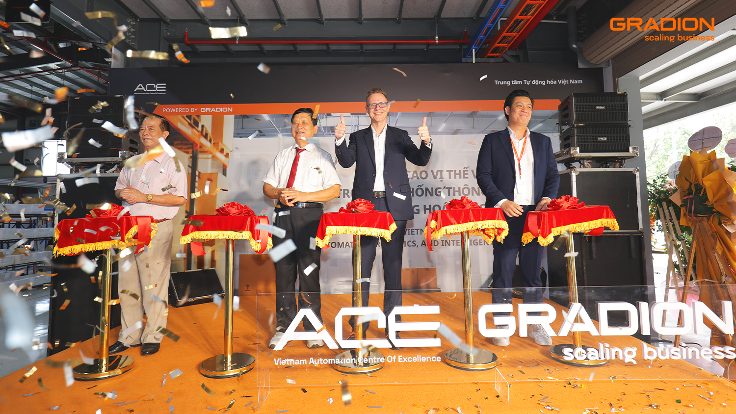 “Ribbon-cutting ceremony at the Vietnam Automation Centre of Excellence (ACE) powered by Gradion, featuring business leaders on stage with confetti celebration “Ribbon-cutting ceremony at the Vietnam Automation Centre of Excellence (ACE) powered by Gradion, featuring business leaders on stage with confetti celebration