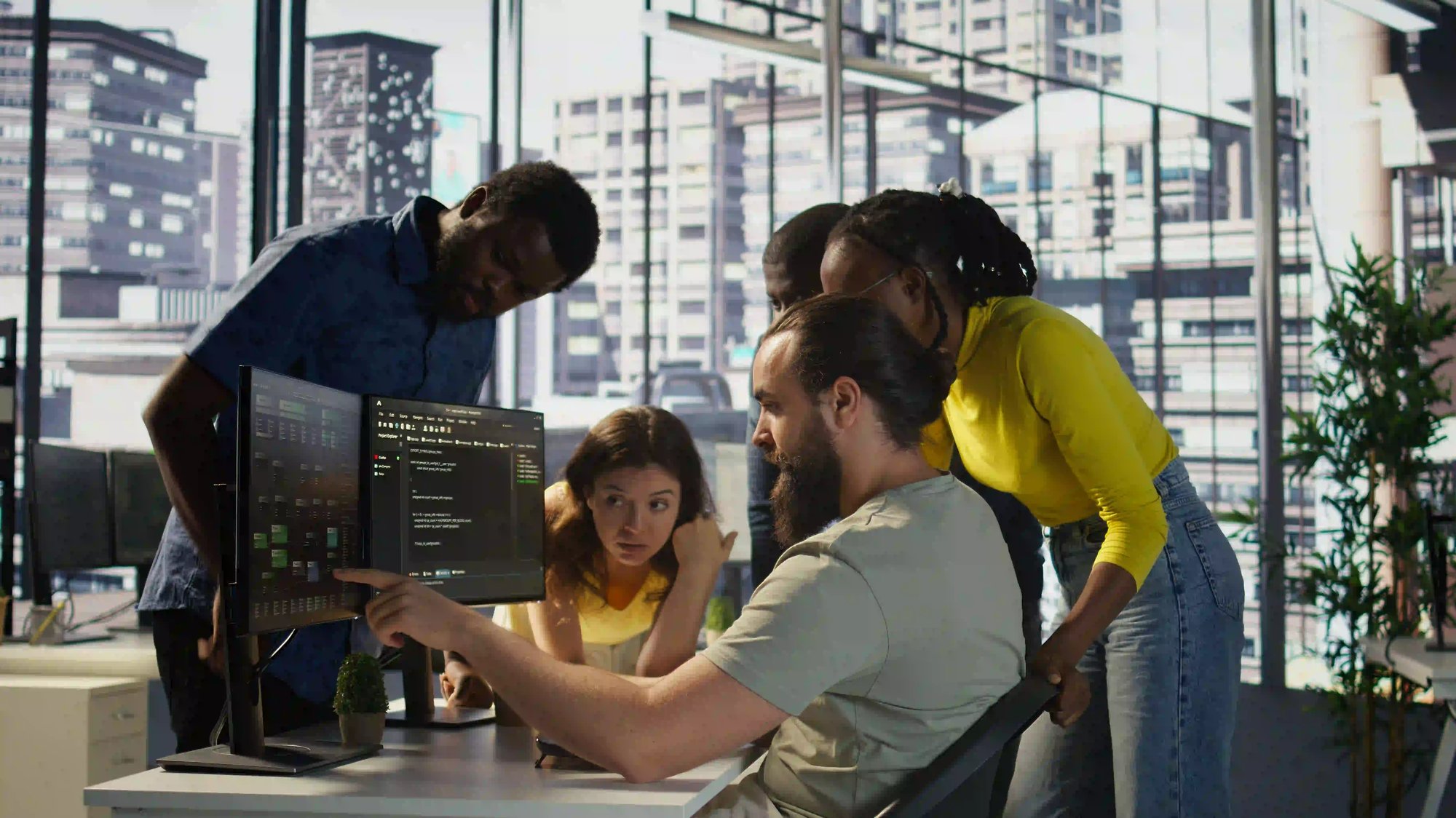 Team collaborating on multiple computer screens in modern office.