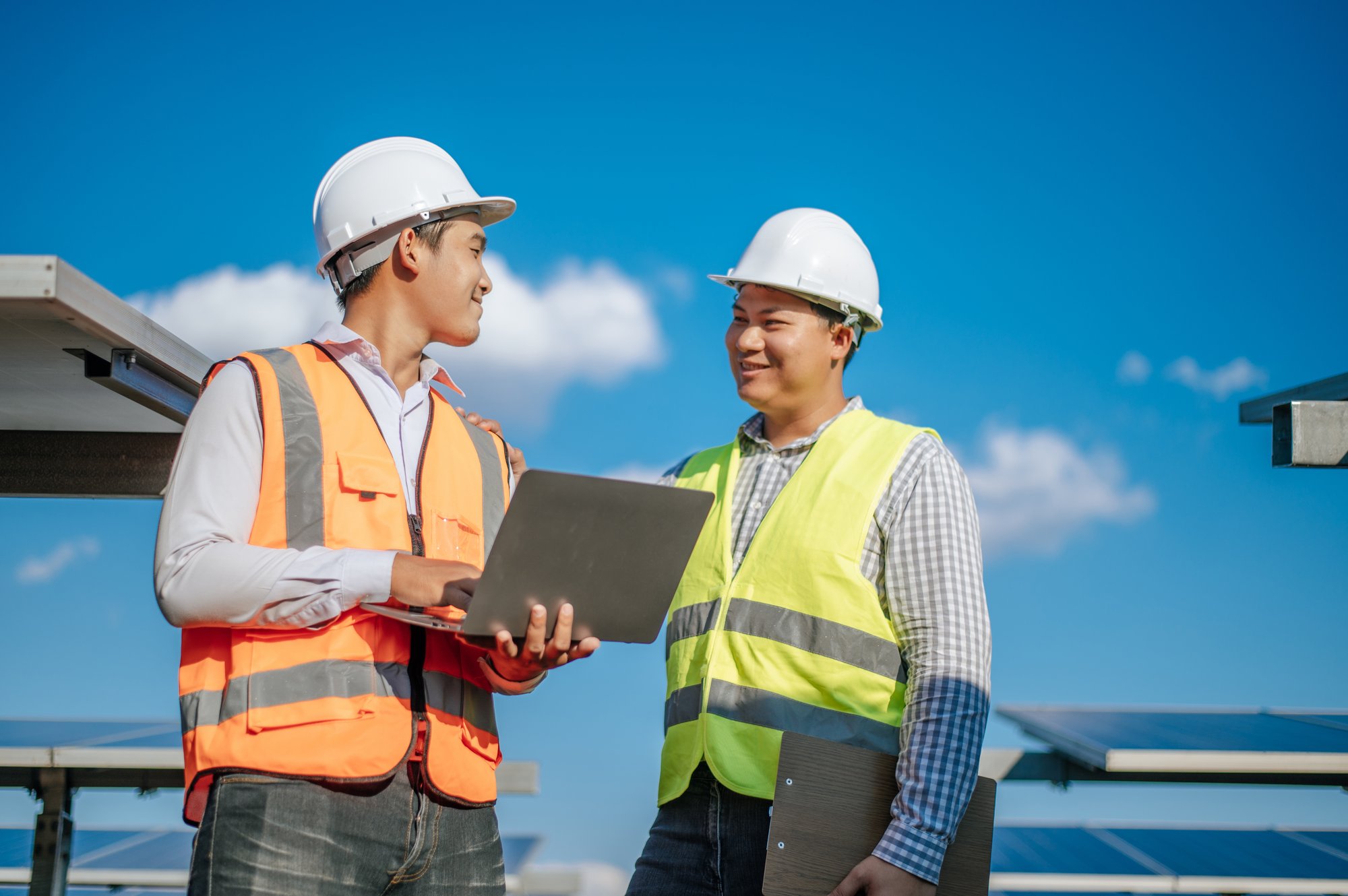 young-asian-technician-man-colleague-safety-uniform-checking-operation-sun-photovoltaic-solar-panel-use-laptop-computer-while-working-solar-farm